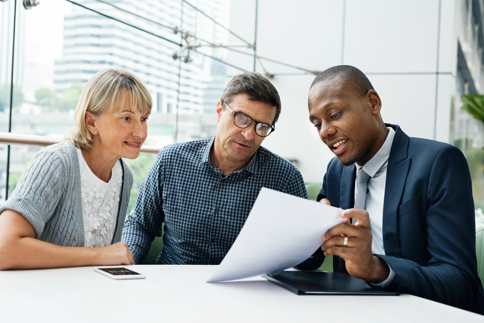  A financial advisor is sitting at a table with a couple, discussing financial planning.